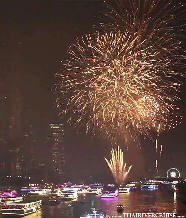 Detailed view of multi-colored red and white firework bursts over the Chao Phraya River, with iconic landmarks like a lit observation wheel and high-rise hotels in the background.